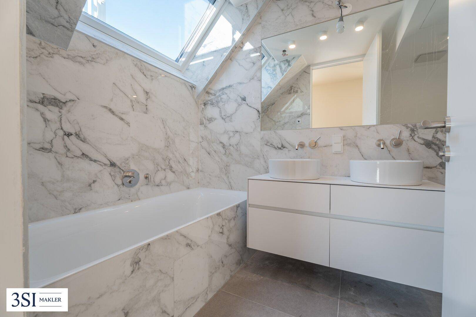 Modernes Badezimmer mit luxuriösen Marmorfliesen, Doppelwaschbecken, Badewanne und Dachfenster.
