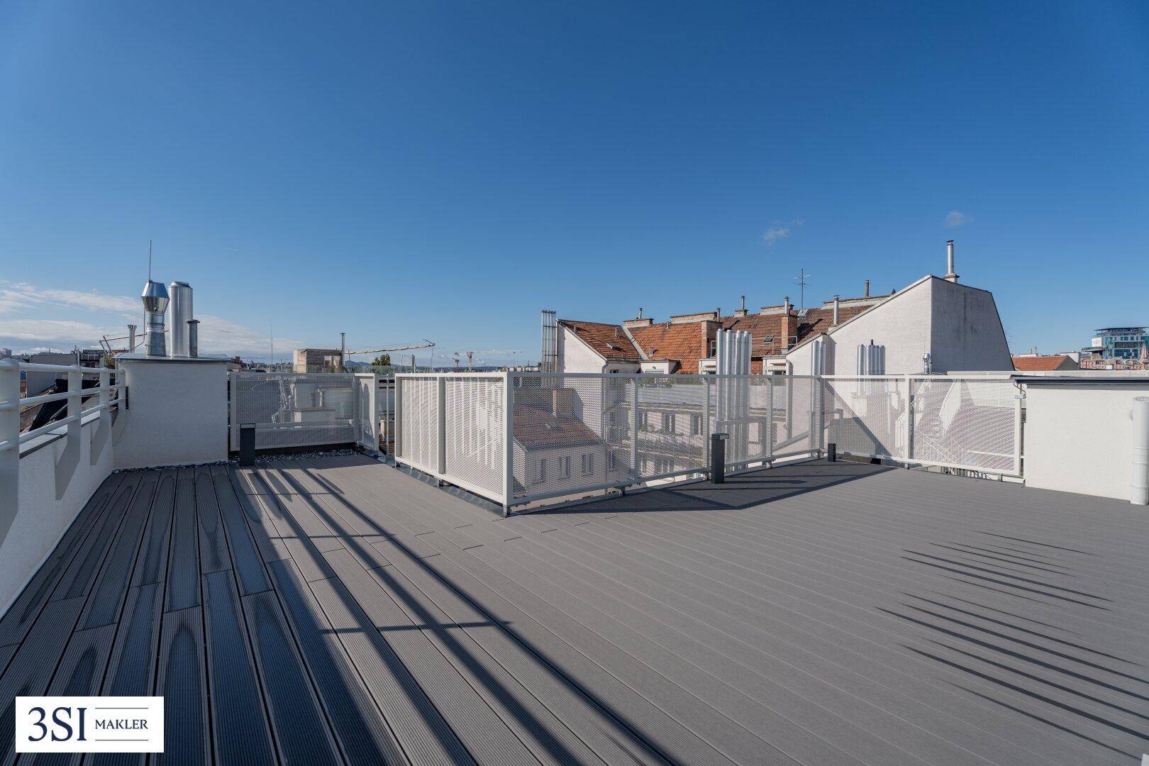 Weitläufige Dachterrasse mit modernem Bodenbelag und Blick über die Dächer der Stadt.