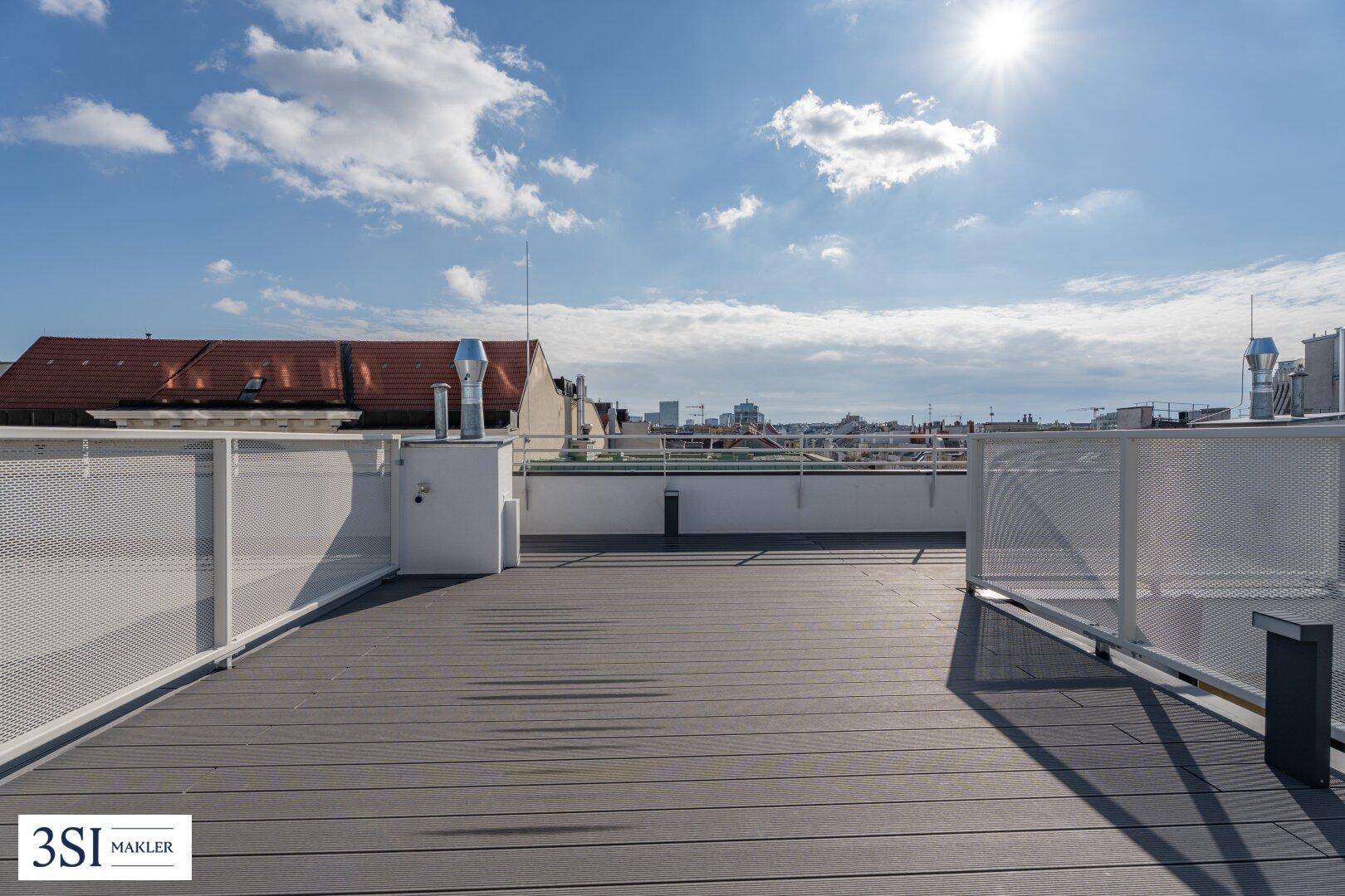 Sonniger Ausblick von der Dachterrasse mit weitem Himmel und Panoramablick über die städtische Umgebung.