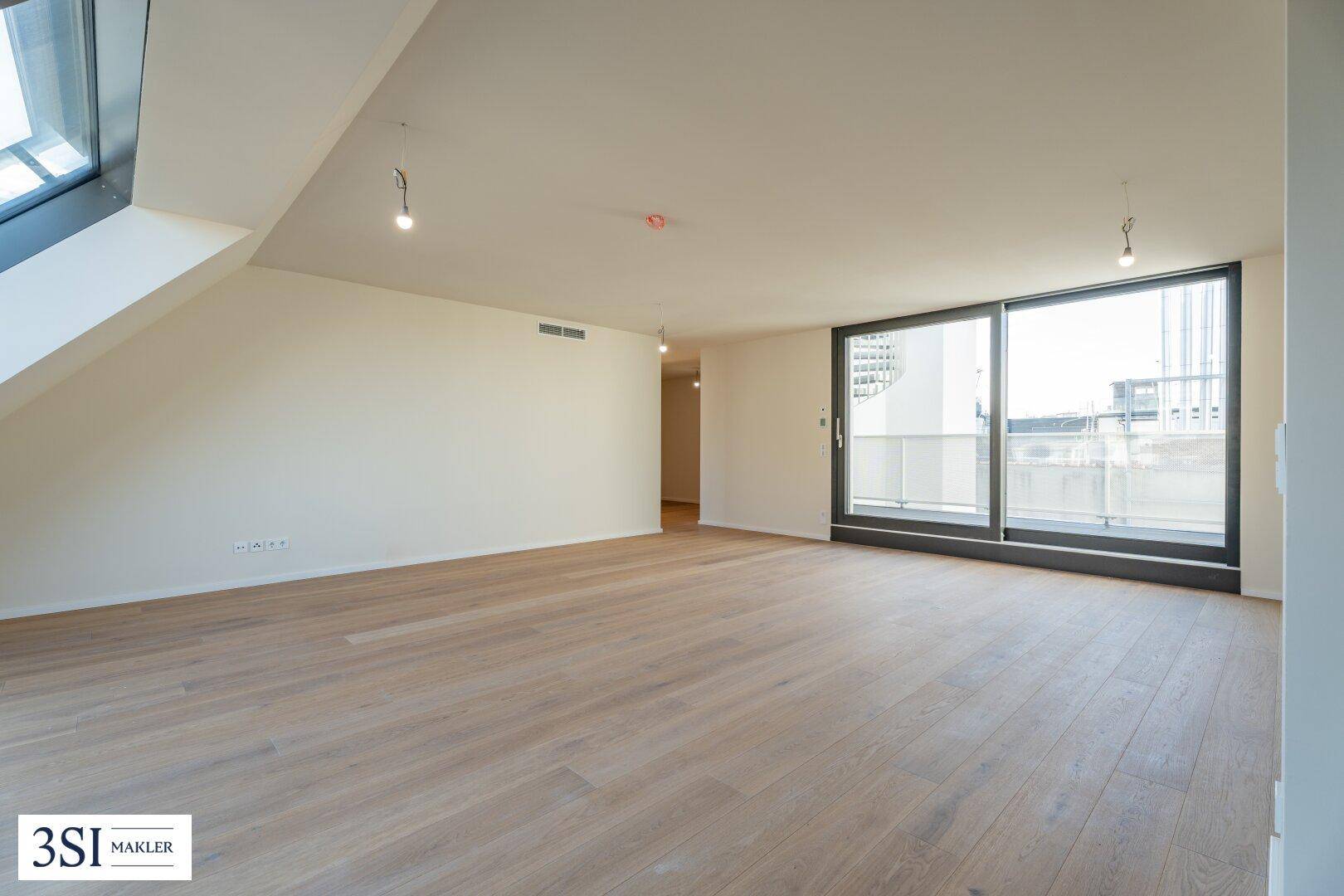 Heller Wohnraum mit Holzboden, Schiebetür zum Balkon und schrägem Dachfenster.