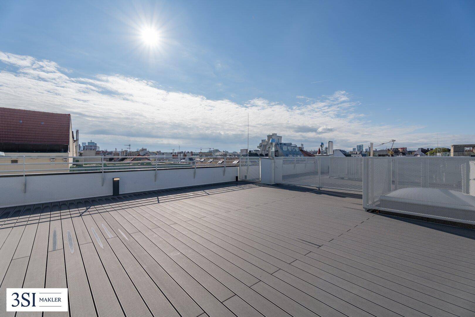 Weitläufige Dachterrasse mit Holzdielenboden und Panoramablick über die Stadt.