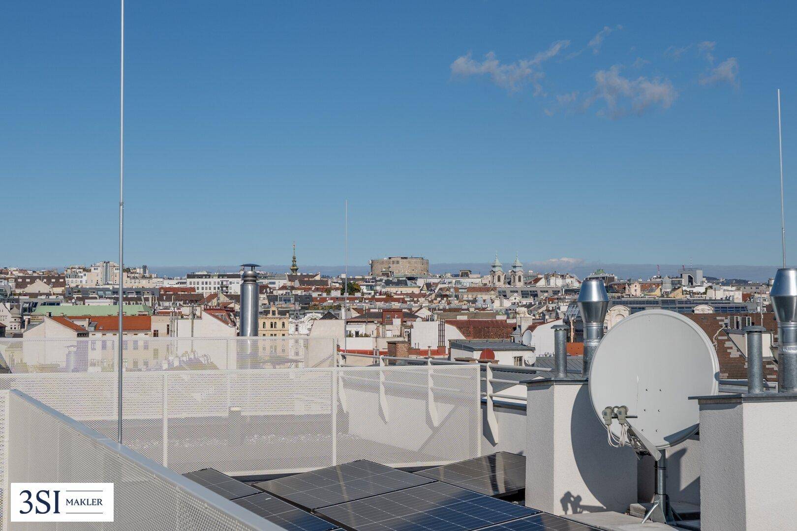 Panoramablick über die Stadt von der Dachterrasse mit sichtbaren Solarmodulen.