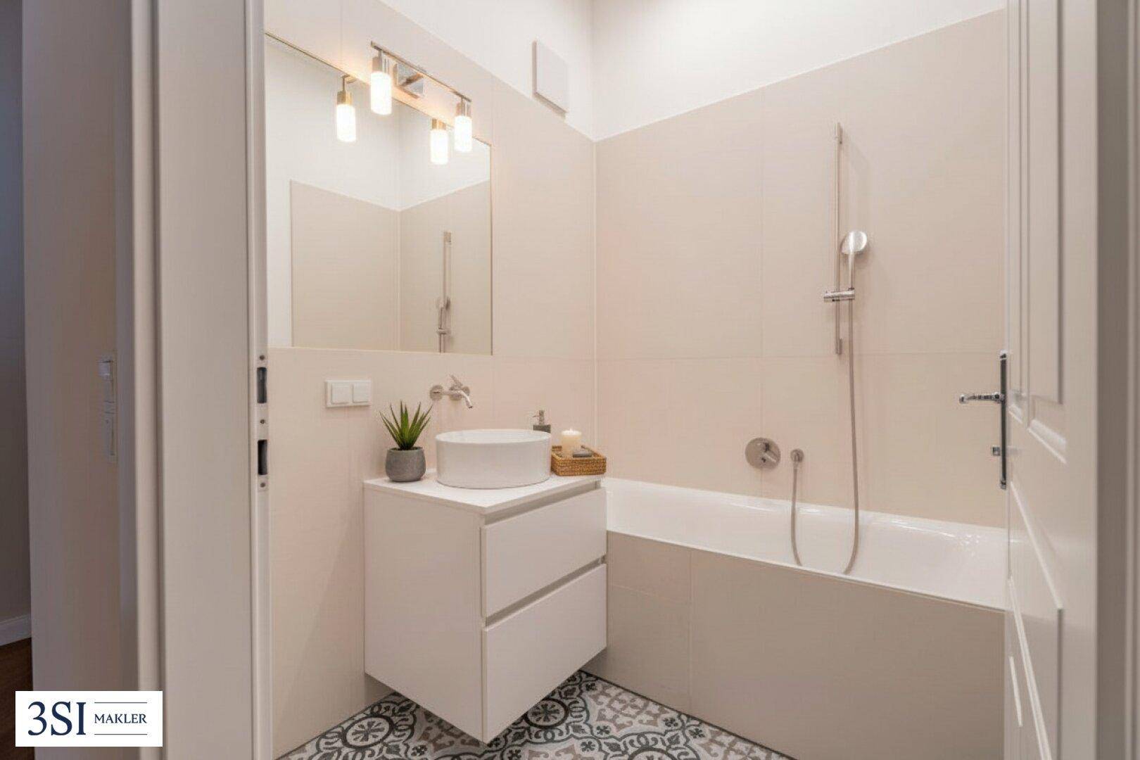 Modernes Badezimmer mit Badewanne, Einzelwaschbecken und gemusterten Bodenfliesen.