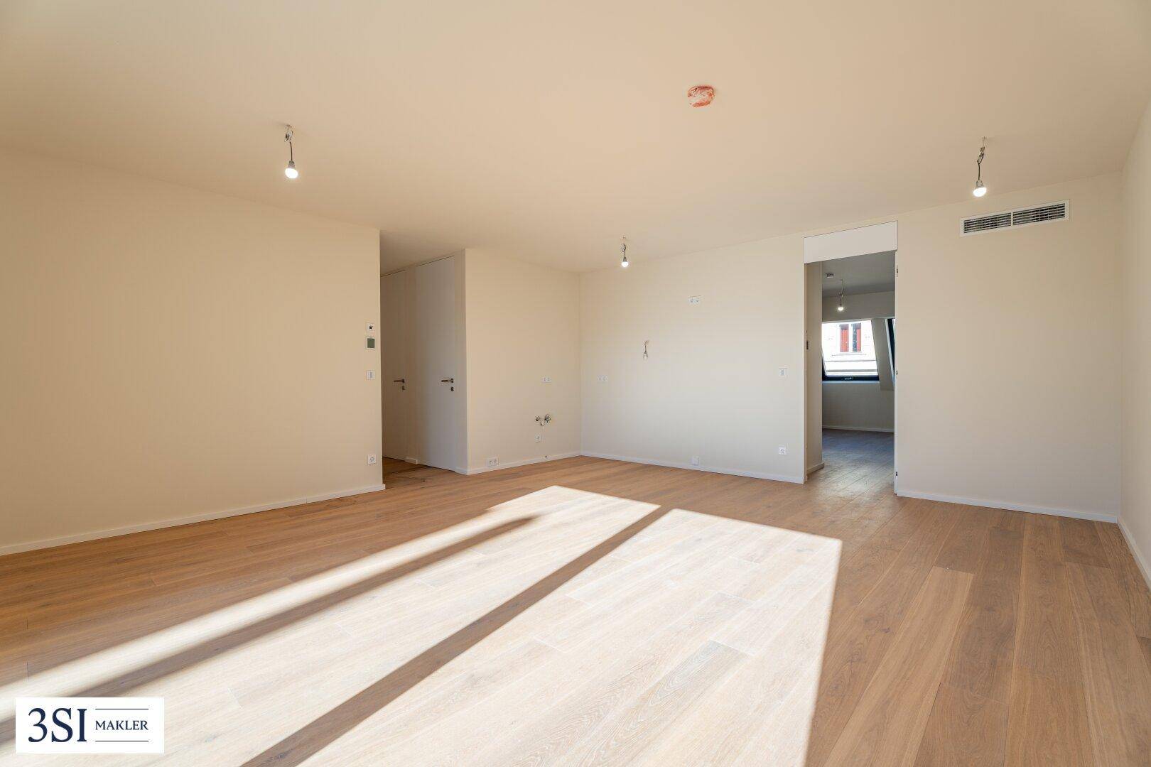 Geräumiges, helles Zimmer mit Holzboden und Zugang zu weiteren Räumen, ideal für flexible Nutzung.