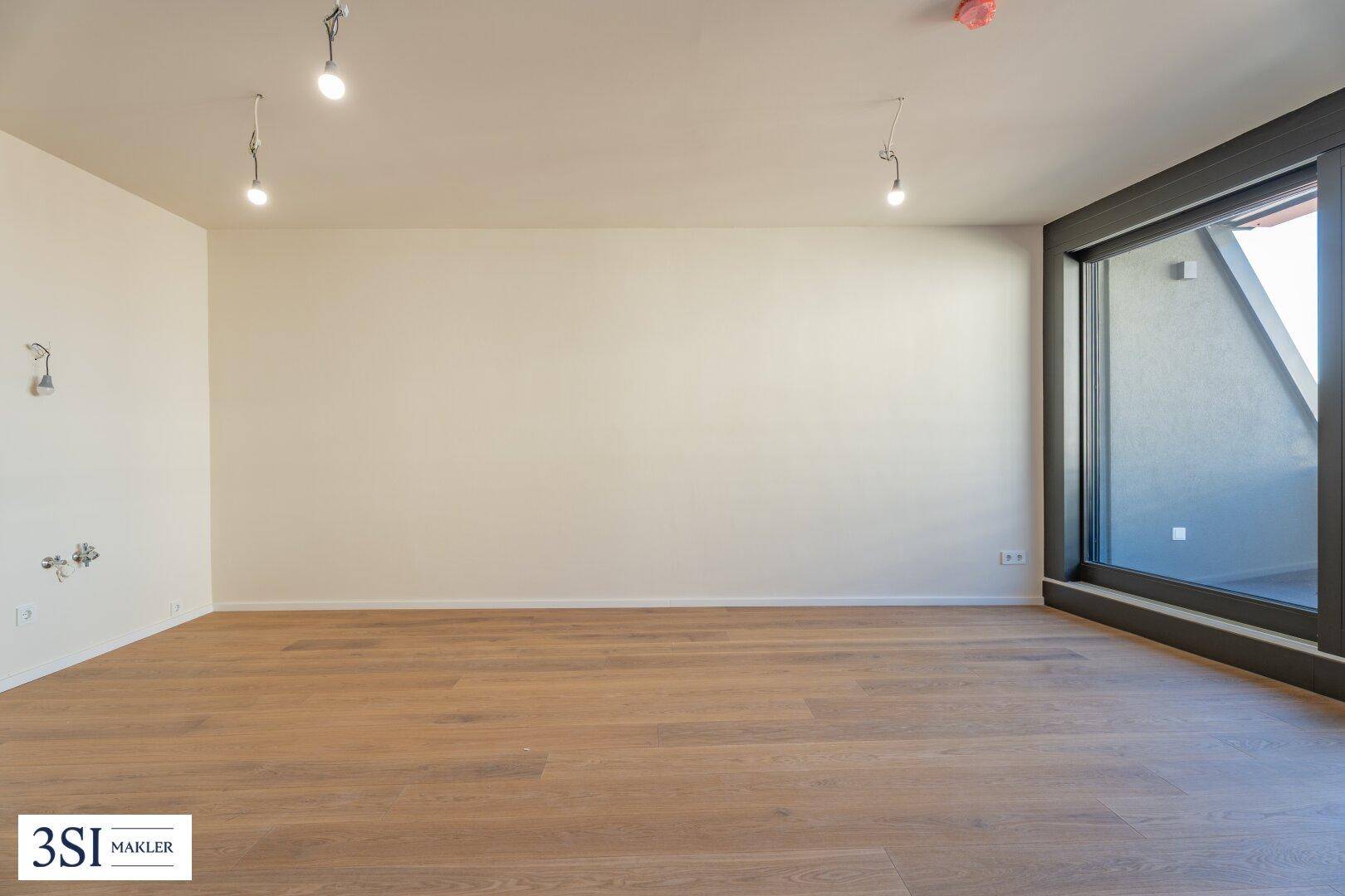 Heller Wohnbereich mit Holzboden und großem Fenster, das viel Tageslicht in den Raum lässt.