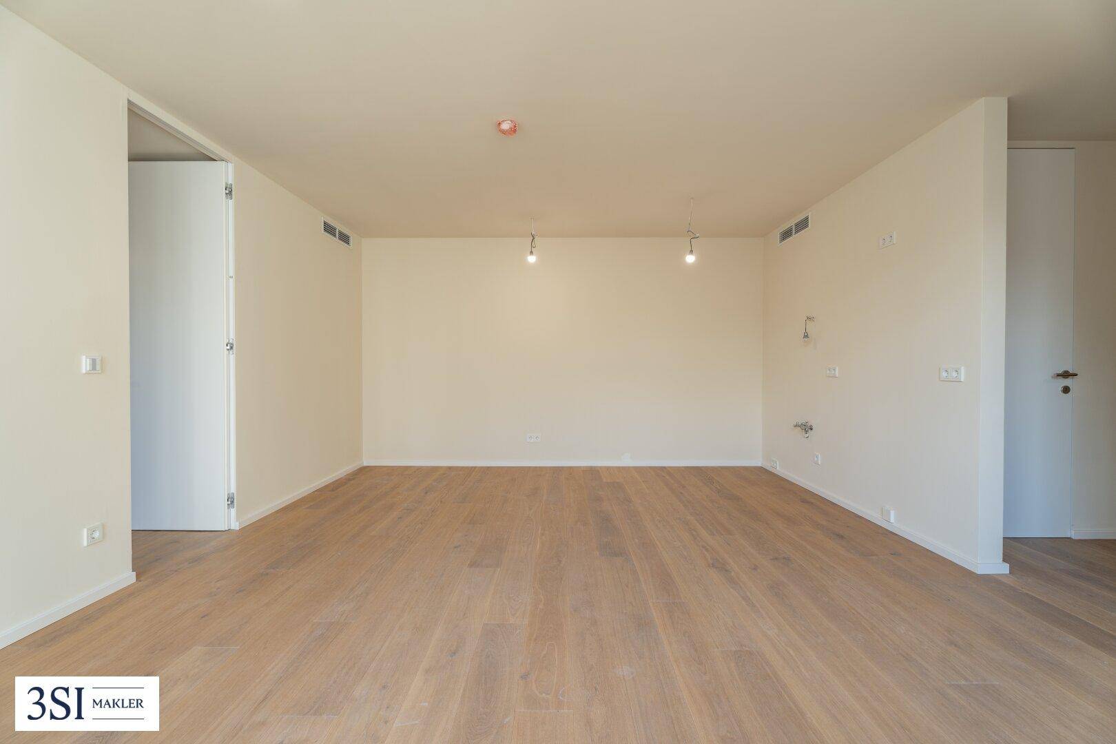Heller, leerer Raum mit Holzboden und weißen Wänden, ideal für individuelle Einrichtung.