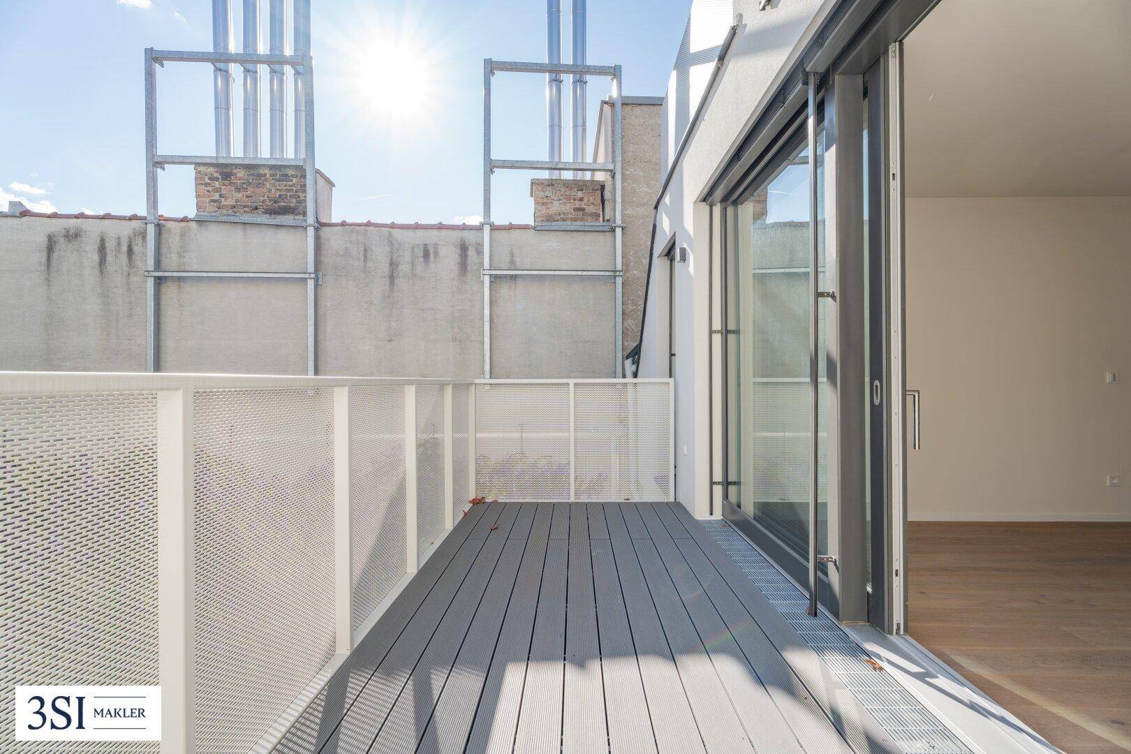 Moderner Balkon mit Holzdielen und Metallgeländer, bietet einen sonnigen Außenbereich.