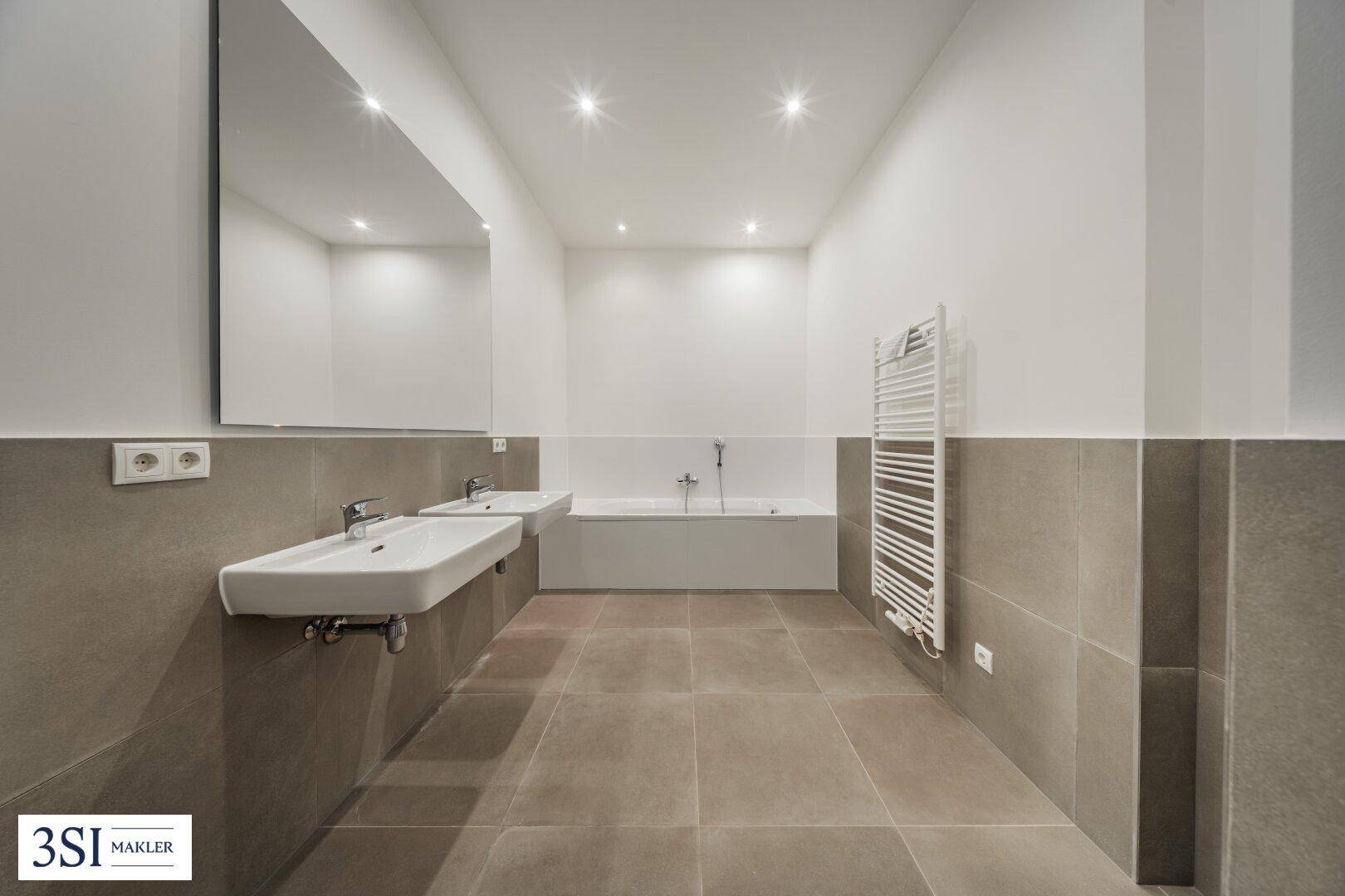 Modernes Badezimmer mit Doppelwaschbecken, Badewanne und beheiztem Handtuchhalter.