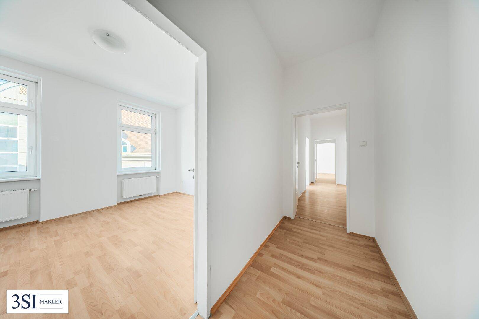 Heller Flur mit Parkettboden, der zu weiteren Zimmern der Wohnung führt.