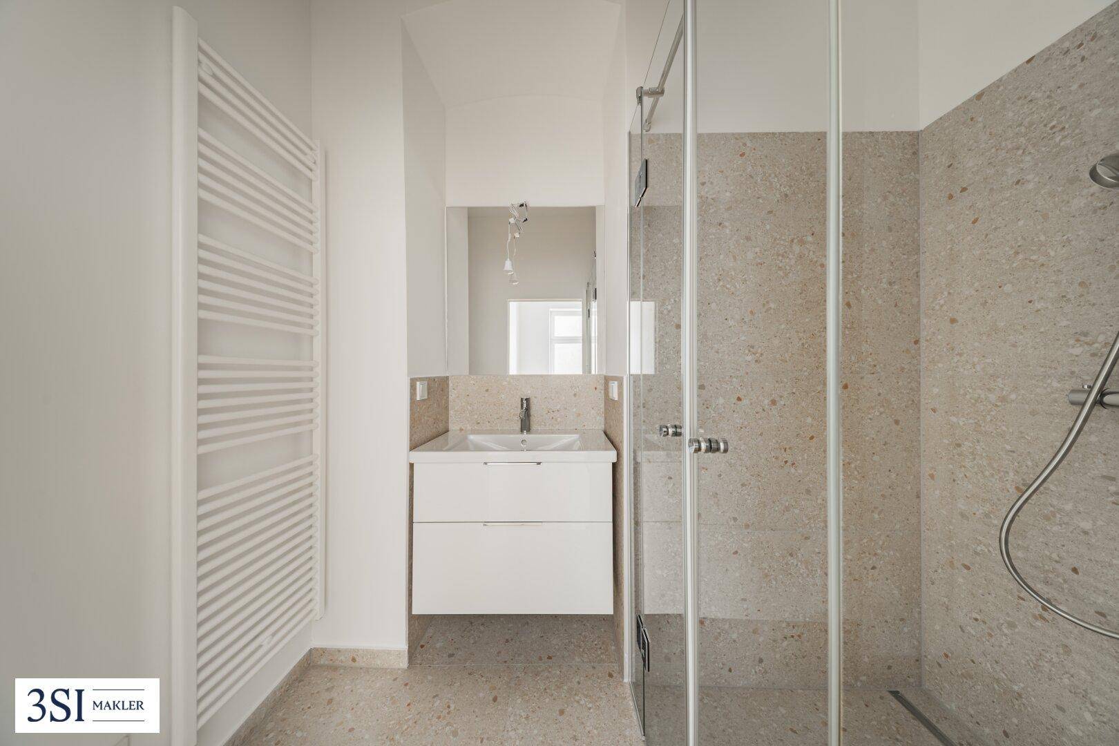 Modernes Badezimmer mit begehbarer Dusche, beheiztem Handtuchhalter und Einzelwaschbecken.