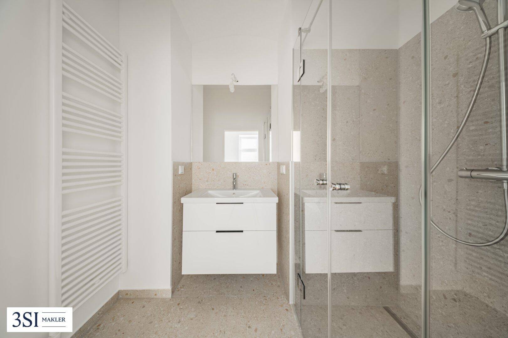 Elegantes Badezimmer mit begehbarer Dusche, beheiztem Handtuchhalter und modernem Waschtisch.
