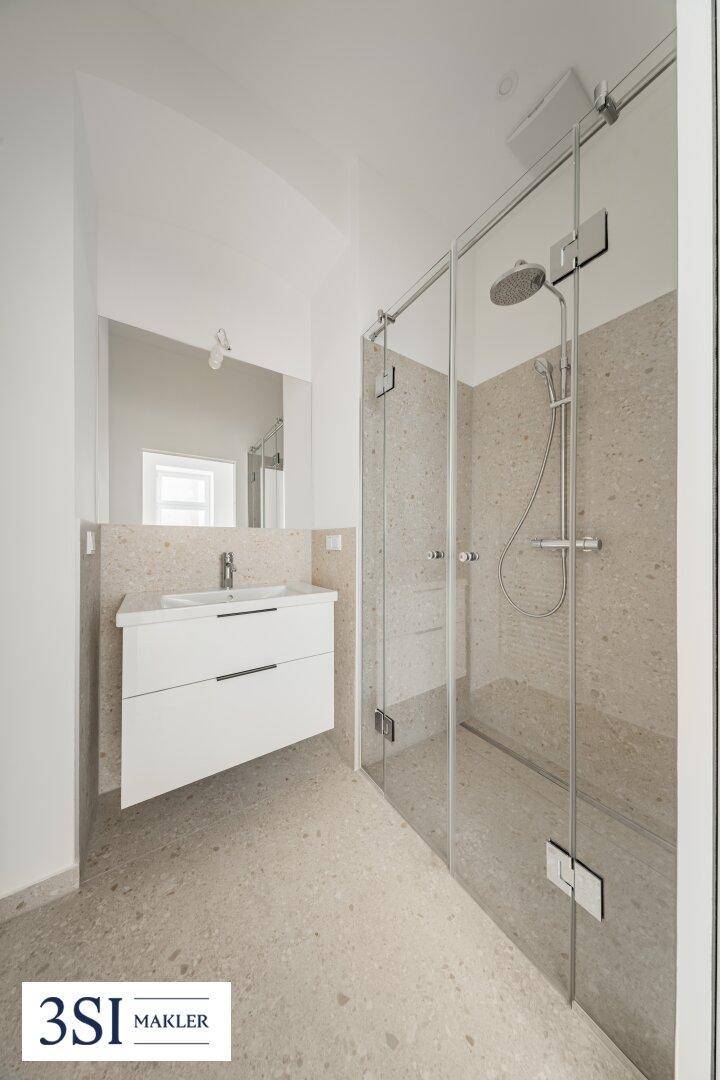 Modernes Badezimmer mit begehbarer Dusche, Einzelwaschbecken und hellen Fliesen.