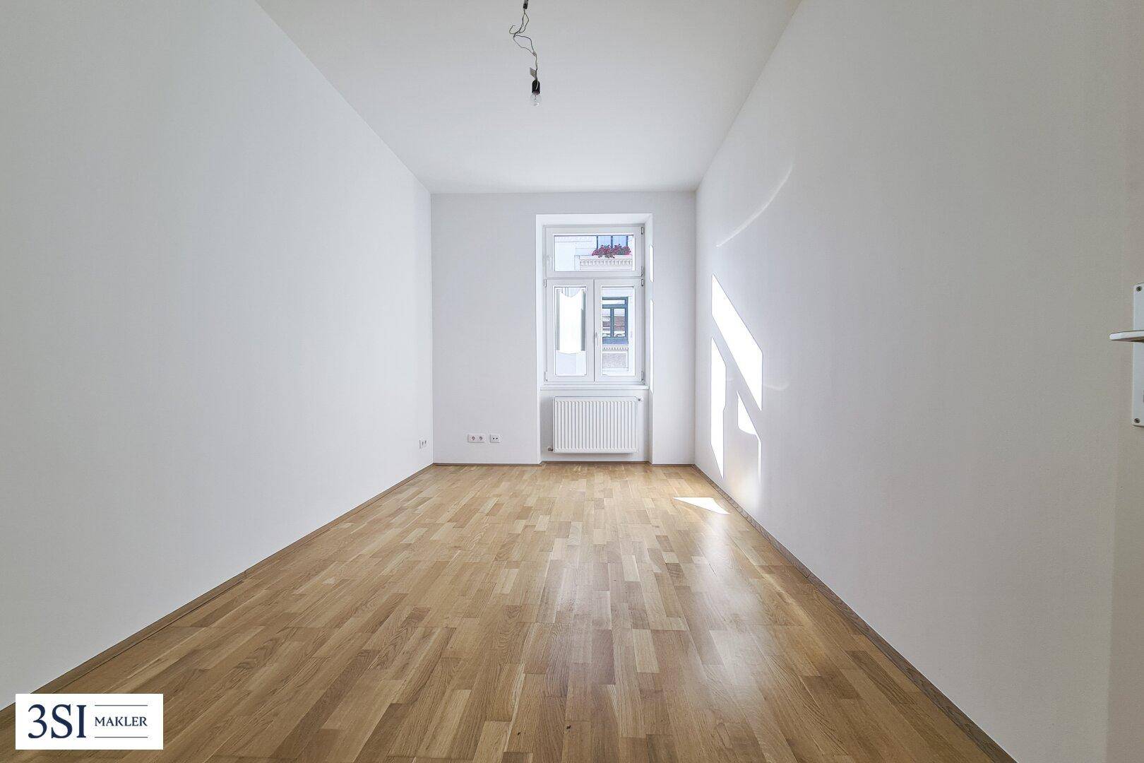 Heller, leerer Raum mit Holzboden und einem Fenster, bietet vielseitige Nutzungsmöglichkeiten.