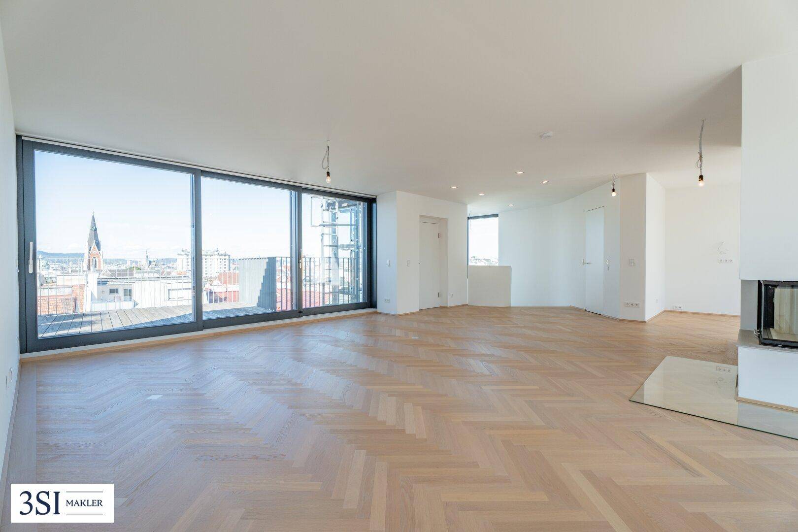 Weitläufiger Wohnbereich mit Zugang zu einer Terrasse durch große Schiebetüren und einem modernen Kamin.