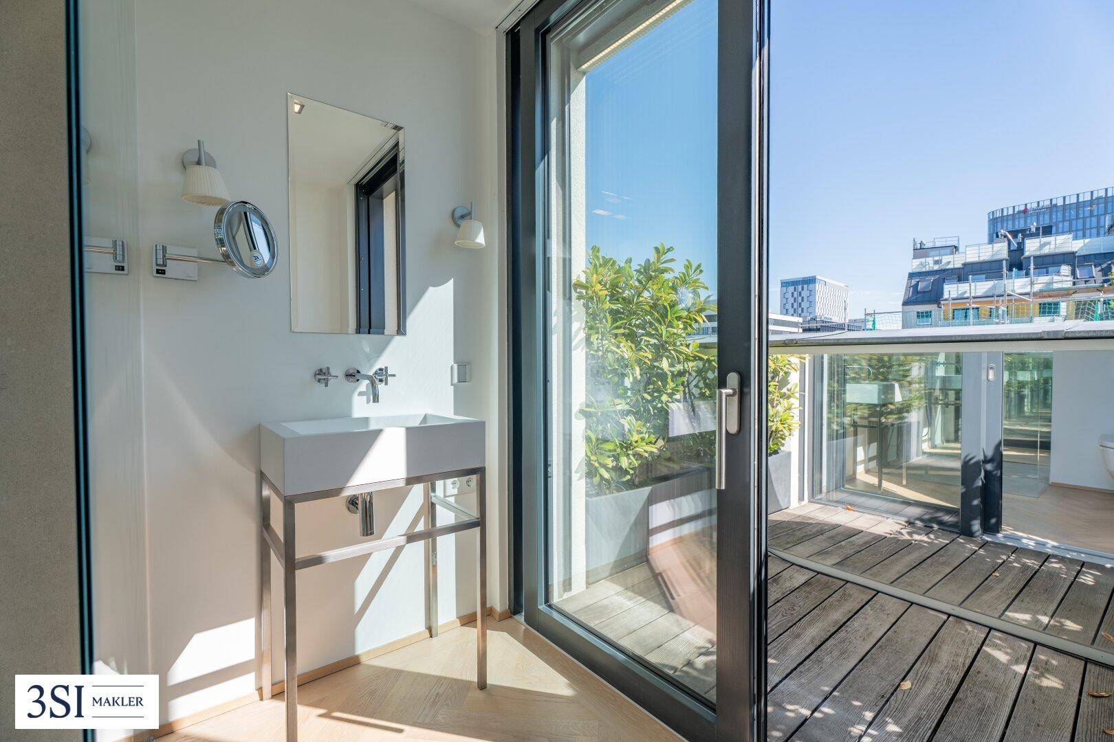 Helles Badezimmer mit Einzelwaschbecken, Spiegel und großem Fenster mit Zugang zu einem Außenbereich.