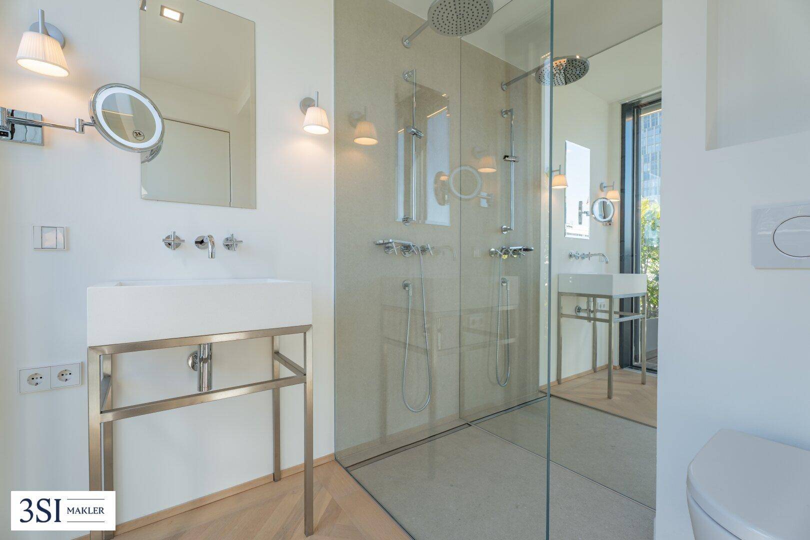 Modernes Badezimmer mit begehbarer Dusche, Einzelwaschbecken und beleuchtetem Spiegel.