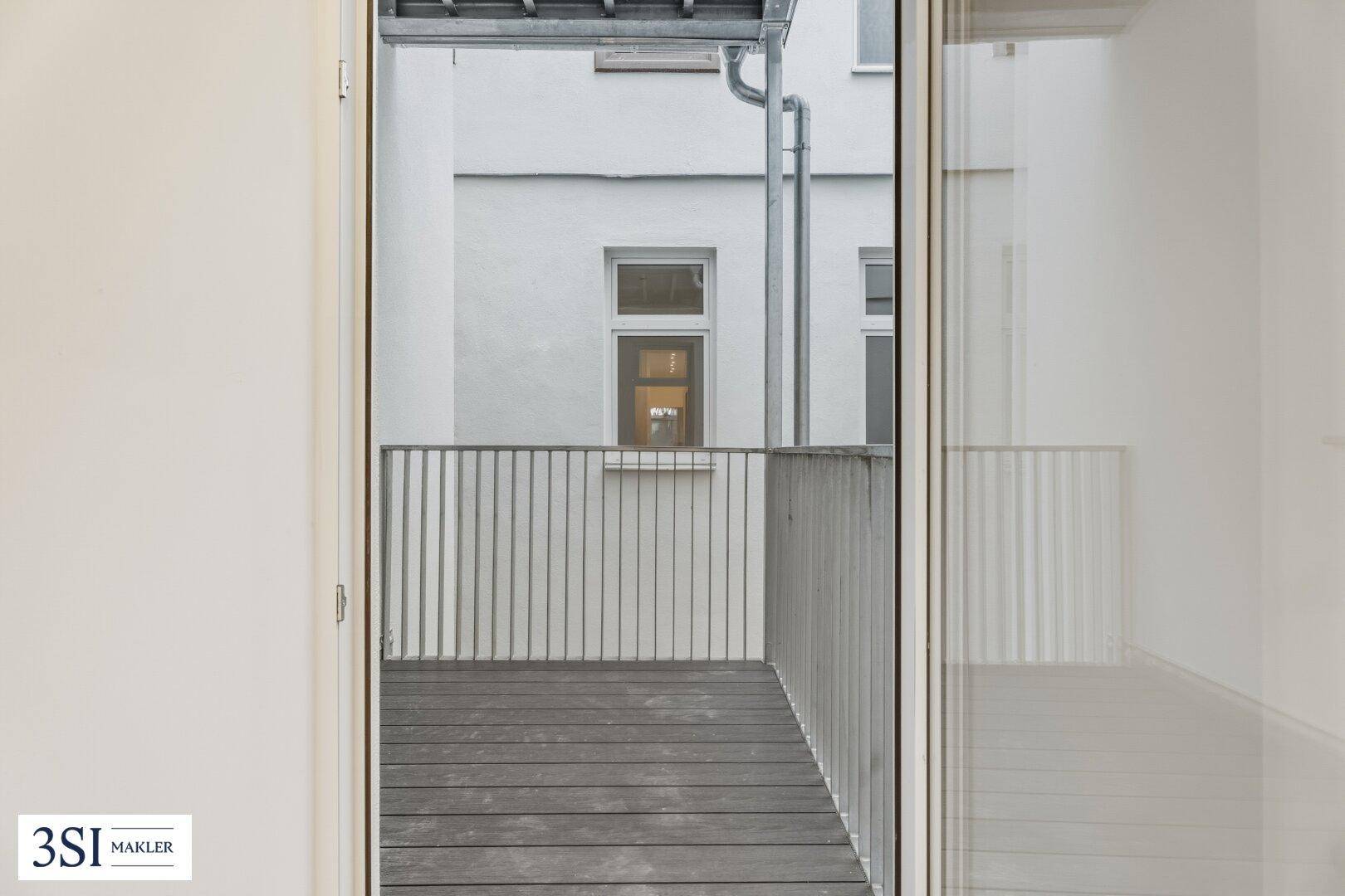 Kleiner Balkon mit Holzboden und Metallgeländer, bietet einen ruhigen Außenbereich.
