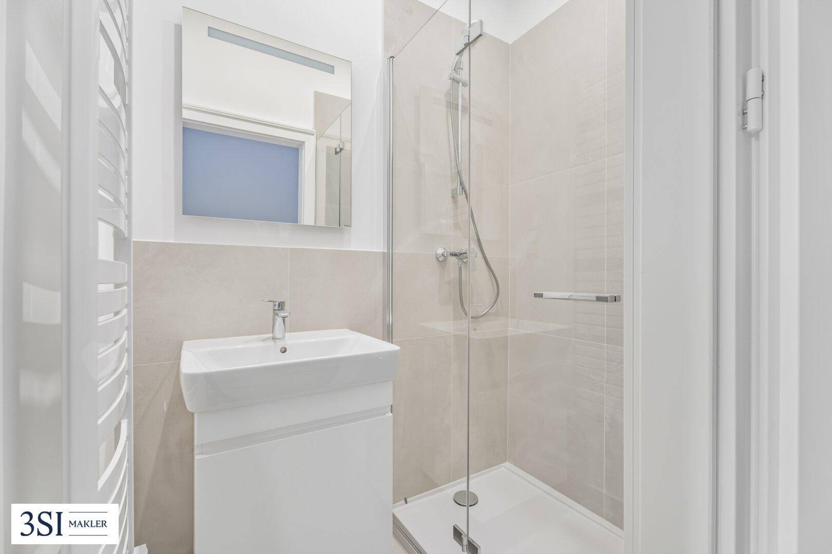Modernes Badezimmer mit begehbarer Dusche, eleganten Fliesen und einem beheizten Handtuchhalter.