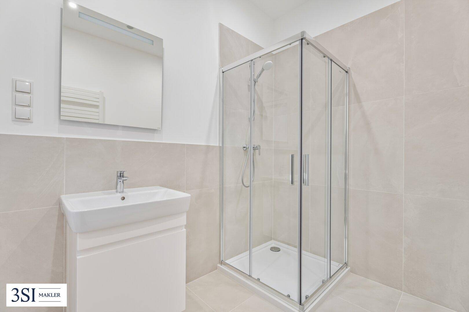 Modernes Badezimmer mit Duschkabine, Waschbecken und hellen Fliesen, in einwandfreiem Zustand.