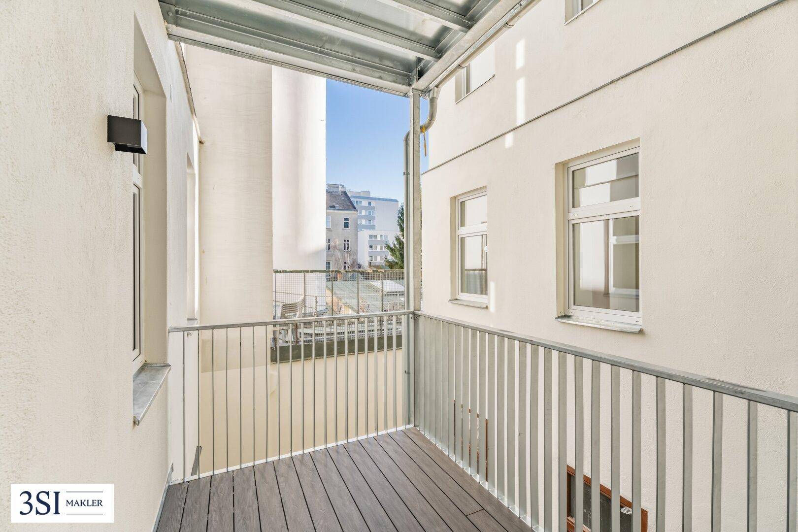 Kleiner Balkon mit Holzboden und Metallgeländer, bietet einen Blick auf die Umgebung.