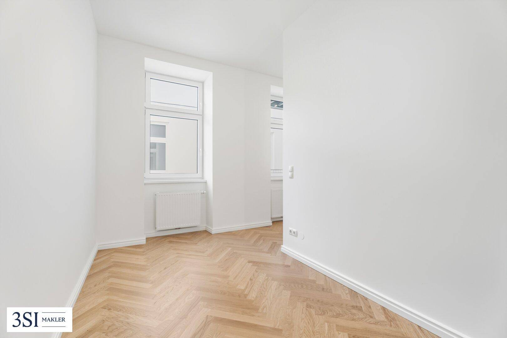 Kleines, helles Zimmer mit Fischgrätparkett und Fenster, ideal als Kinderzimmer oder Büro.