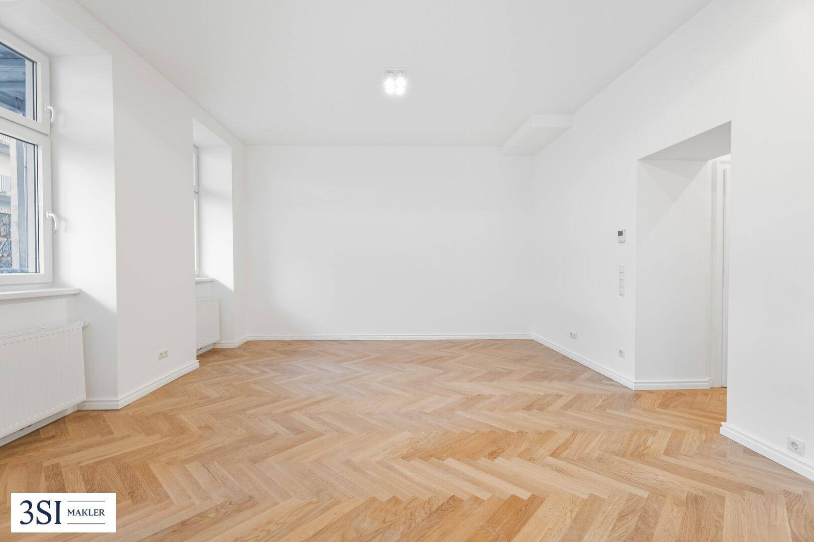 Heller, leerer Raum mit klassischem Fischgrätparkett und weißen Wänden, ideal für neue Einrichtungsideen.