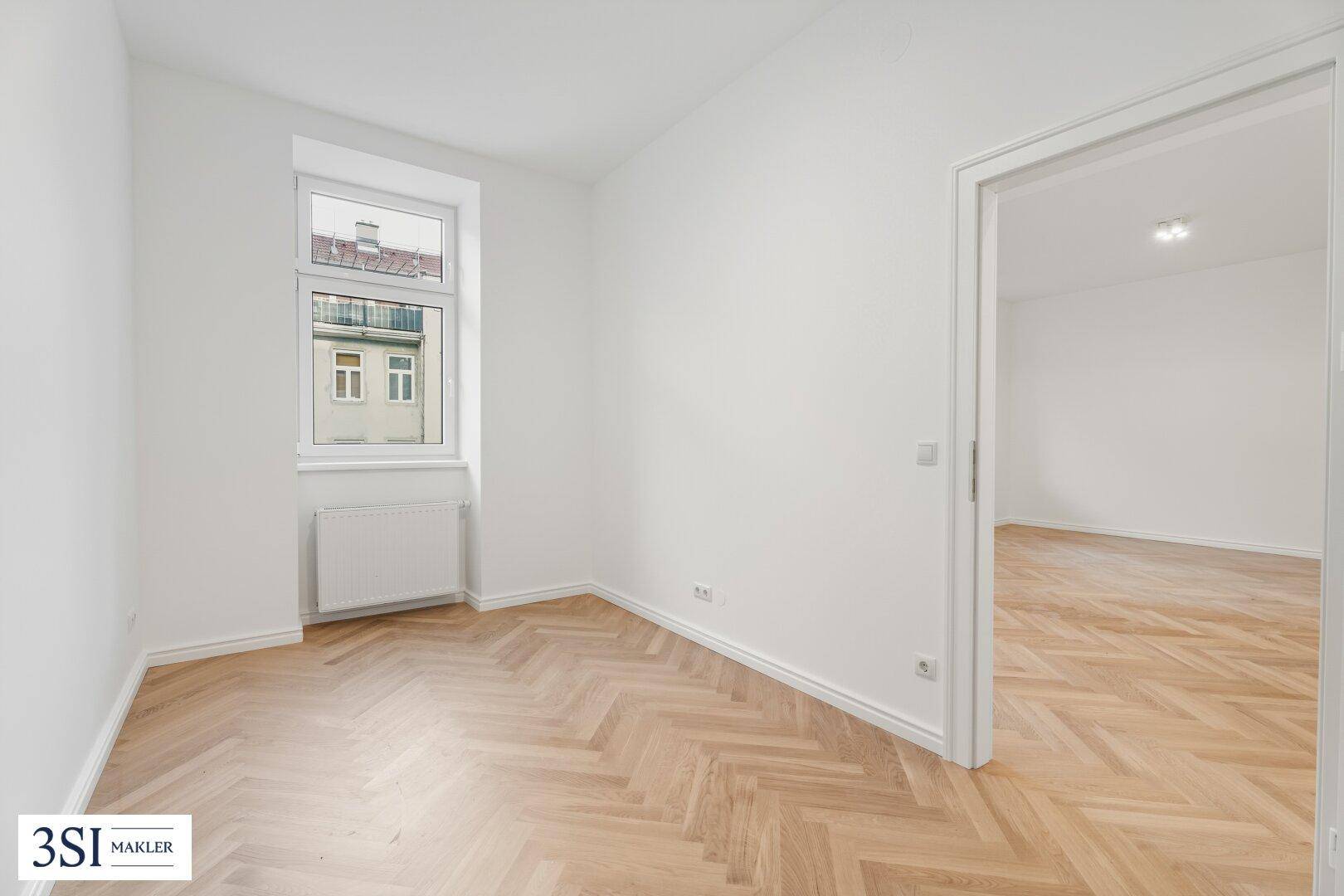 Gemütliches Schlafzimmer mit Fischgrätparkett und einem Fenster, das einen Blick nach draußen bietet.