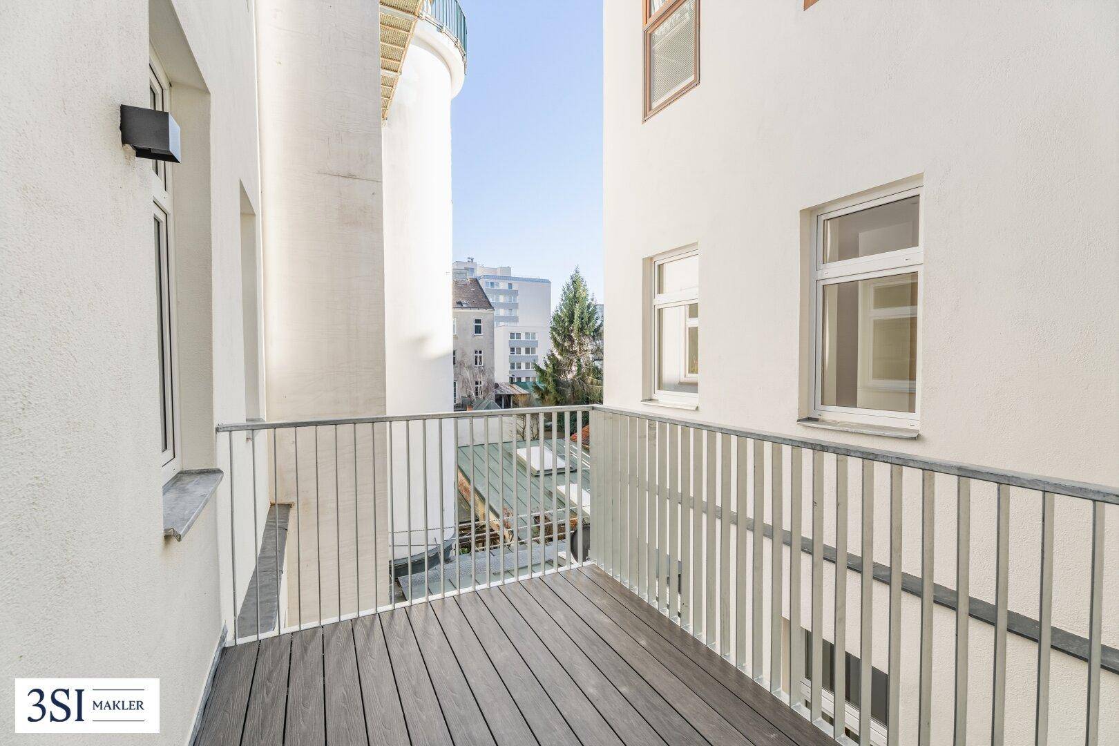 Moderner Balkon mit Holzboden und Metallgeländer, bietet einen Blick auf die Umgebung.