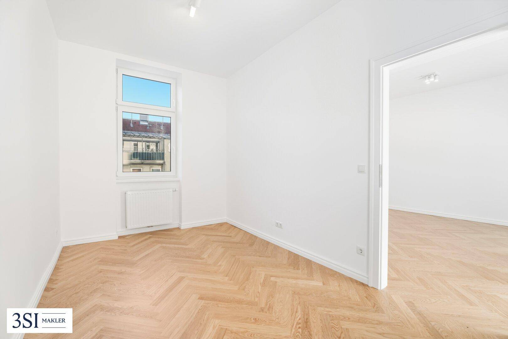 Ruhiges Schlafzimmer mit hellem Fischgrätparkett und einem Fenster mit Blick nach draußen.