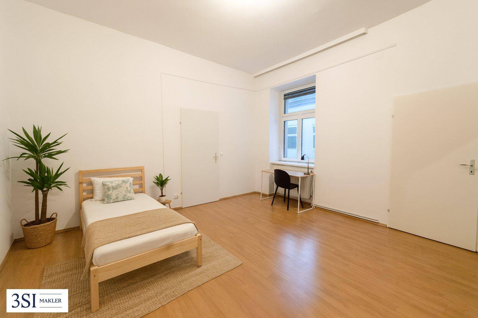 Helles Schlafzimmer mit Einzelbett, Schreibtisch und Laminatboden, bietet vielseitige Nutzungsmöglichkeiten.