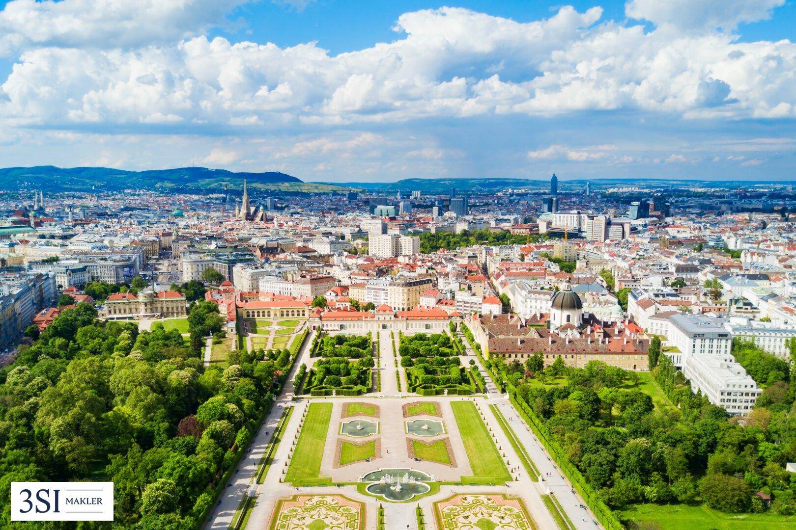 Panoramablick auf eine historische Stadt mit einem prächtigen Schloss und weitläufigen Gärten.