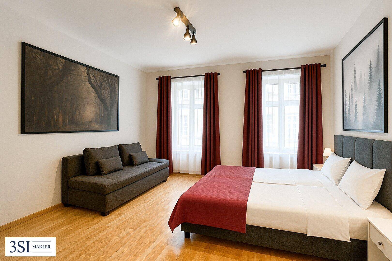 Geräumiges Schlafzimmer mit Holzboden, bequemer Schlafcouch und zwei großen Fenstern für viel Licht.