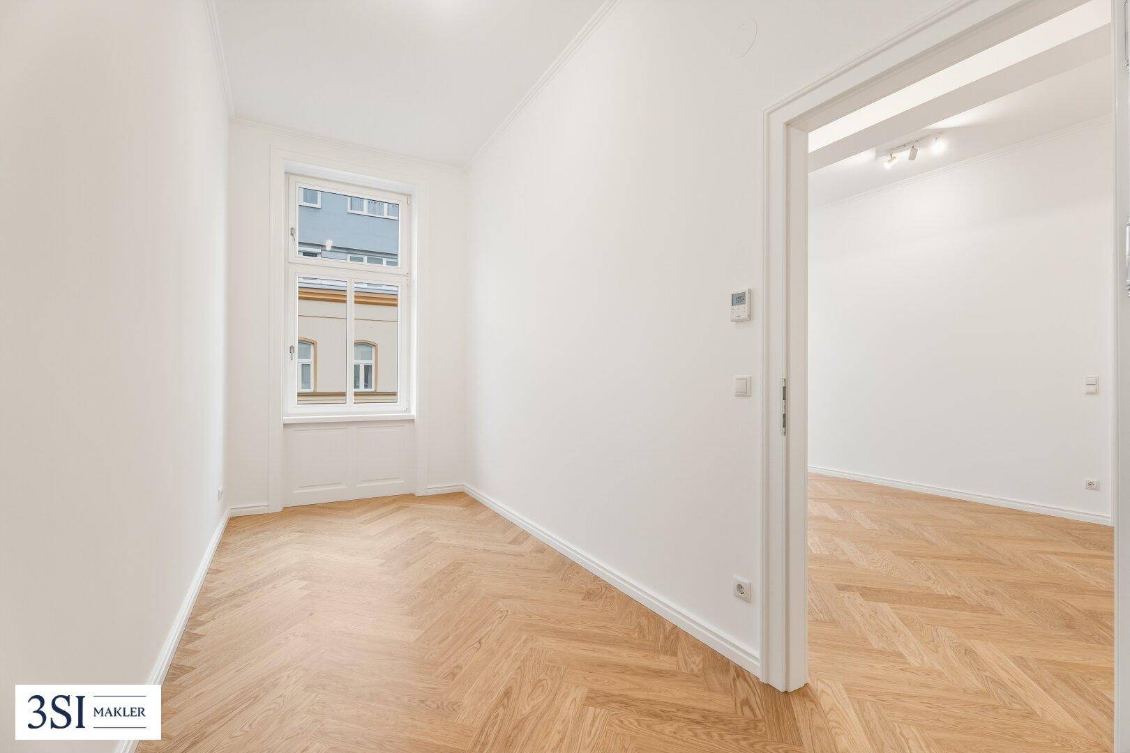 Ruhiges Zimmer mit Fischgrätparkett und einem Fenster, ideal als Schlaf- oder Arbeitszimmer.