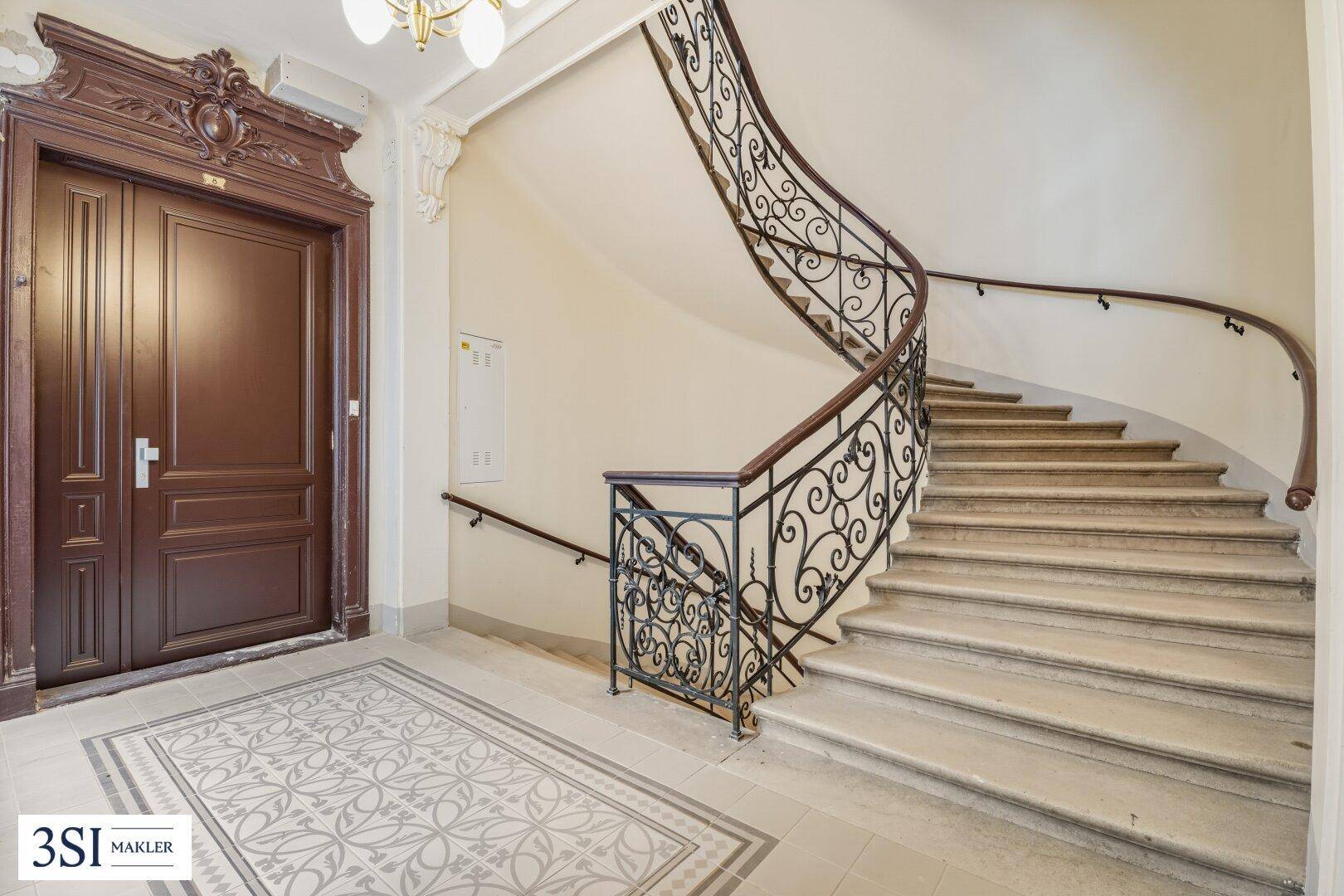 Prunkvolles Treppenhaus mit kunstvollem Geländer und verzierten Eingangstüren im historischen Altbau.