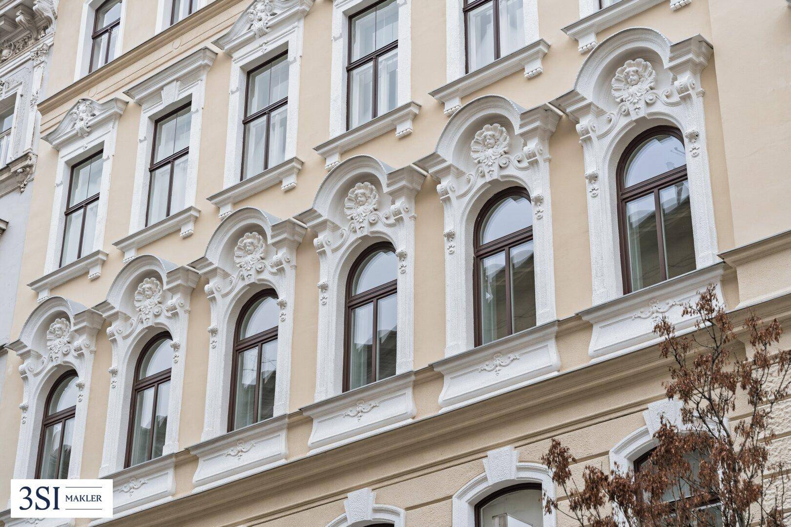 Nahaufnahme der historischen Fassade mit detaillierten Stuckelementen und klassischen Fenstern.