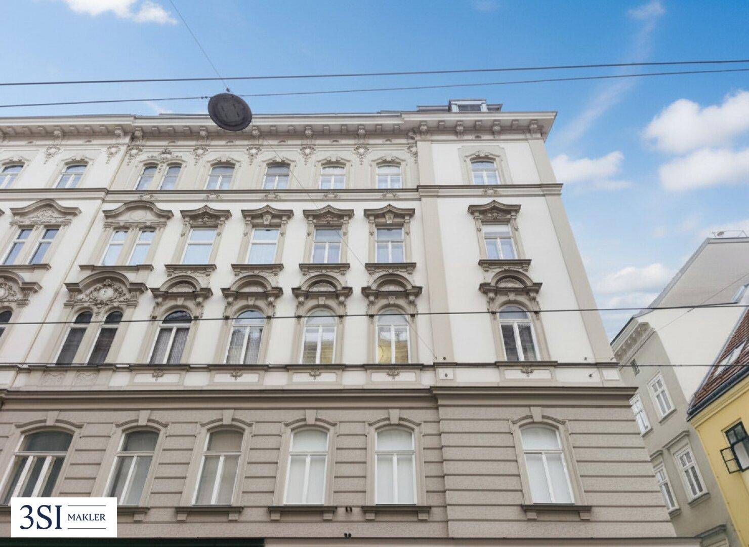Detailansicht der reich verzierten Fassade eines historischen Gebäudes unter blauem Himmel.