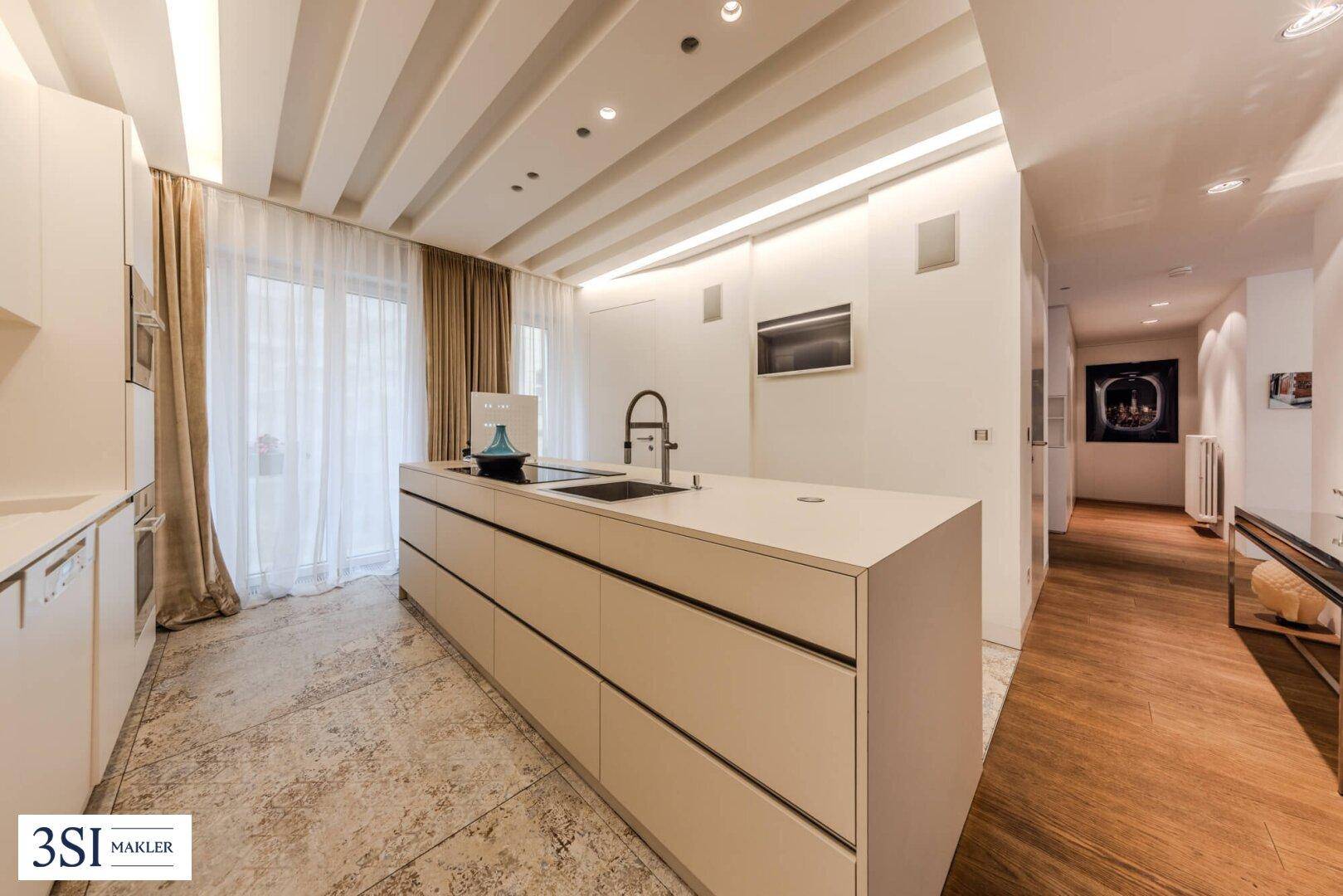 Elegante Küche mit großer Kücheninsel, viel Stauraum und Zugang zum Flur.