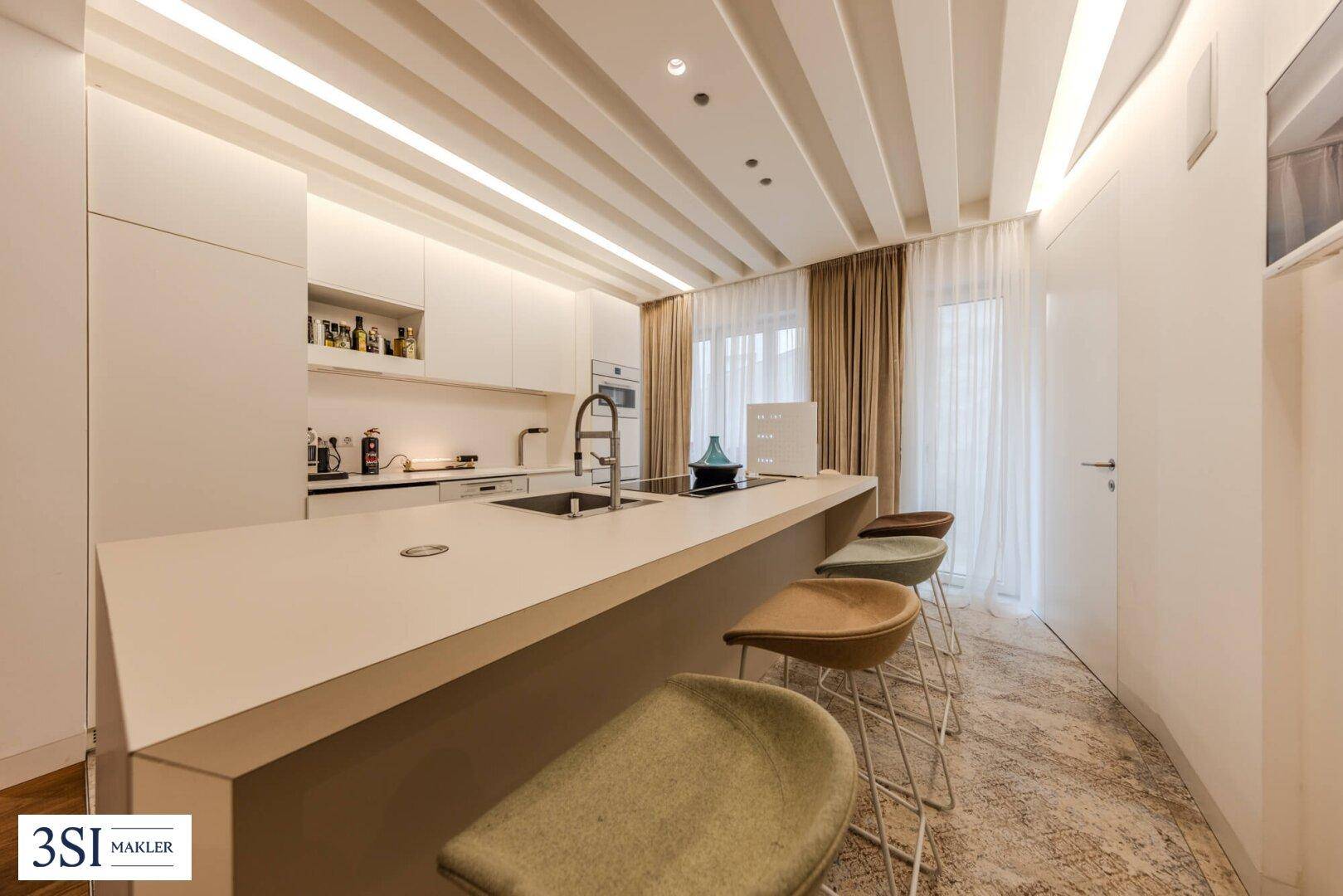 Moderne Küche mit Kücheninsel, integrierten Geräten und hellem Design.