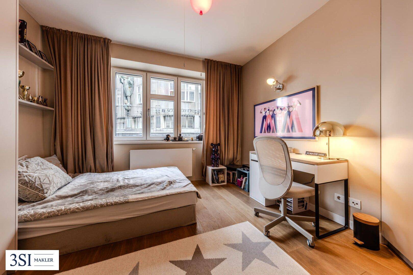 Gemütliches Schlafzimmer mit Holzboden, großem Fenster und Schreibtisch.