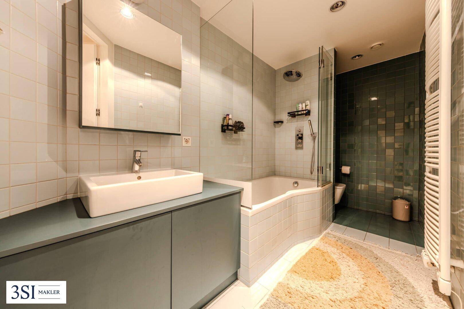 Badezimmer mit Badewanne, Dusche und hellblauen Fliesen.