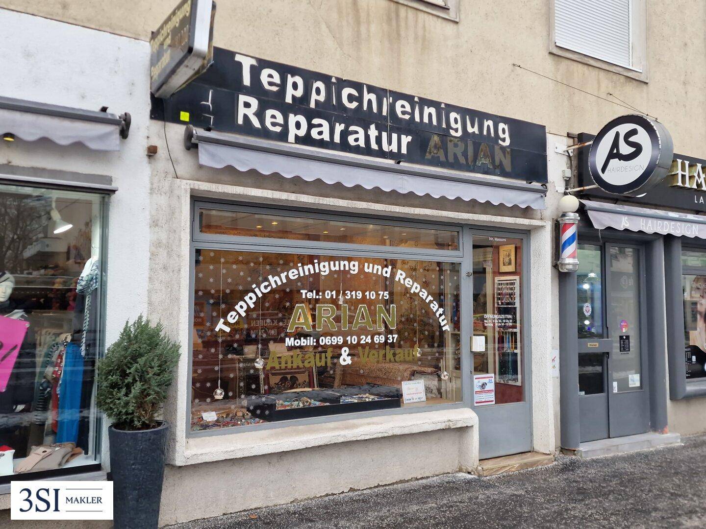 Nahaufnahme eines Teppichreinigungsgeschäfts mit Schaufenster und Beschilderung an einer Geschäftsstraße.