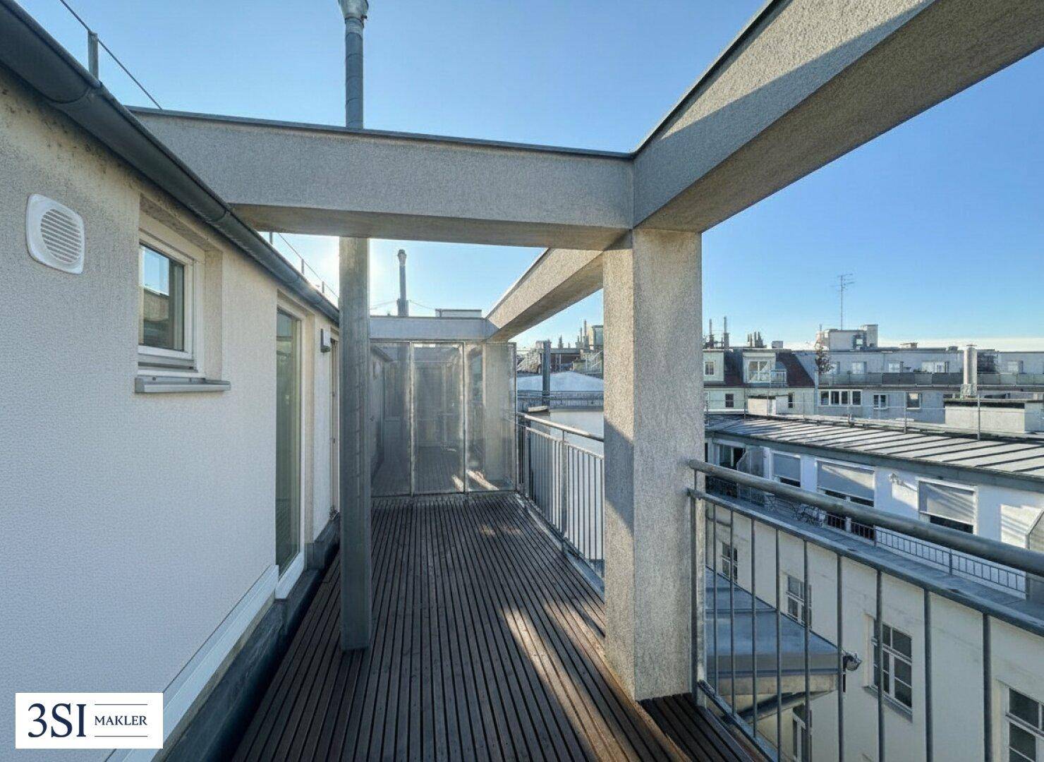 Geräumige Dachterrasse mit Holzboden und weitem Blick über die umliegenden Dächer der Stadt.