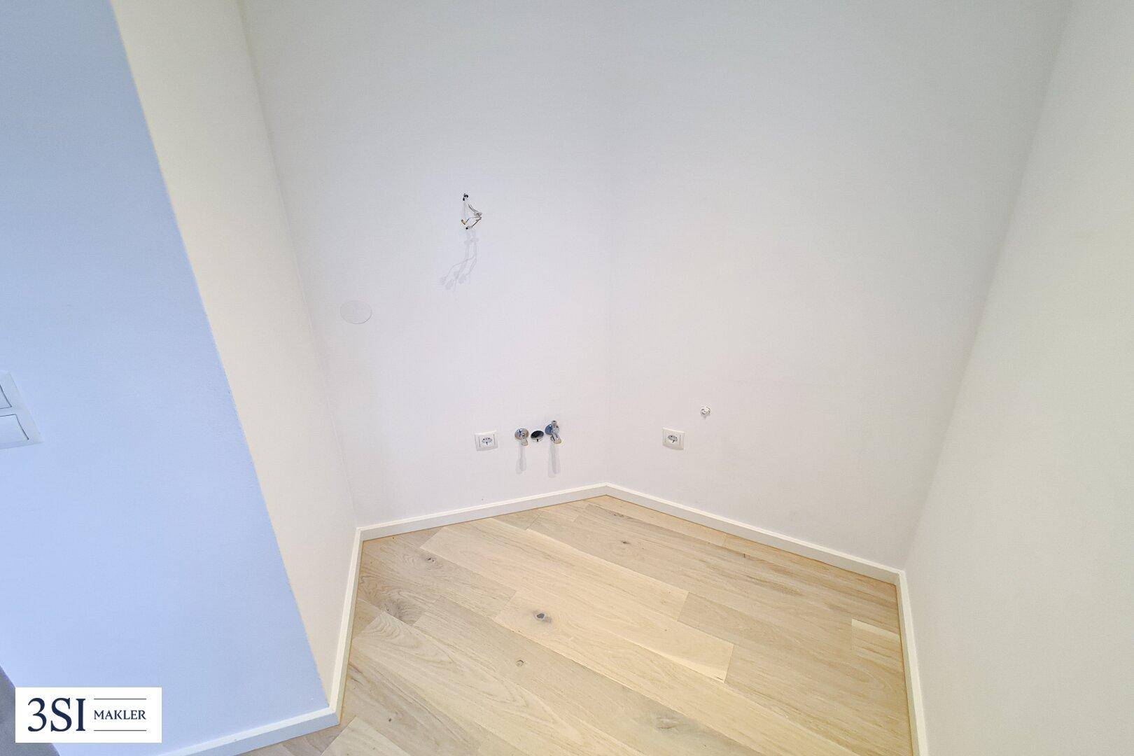 Ecke eines Raumes mit Anschlüssen für Wasser und Strom, ideal für eine Küchenzeile oder Waschmaschine.
