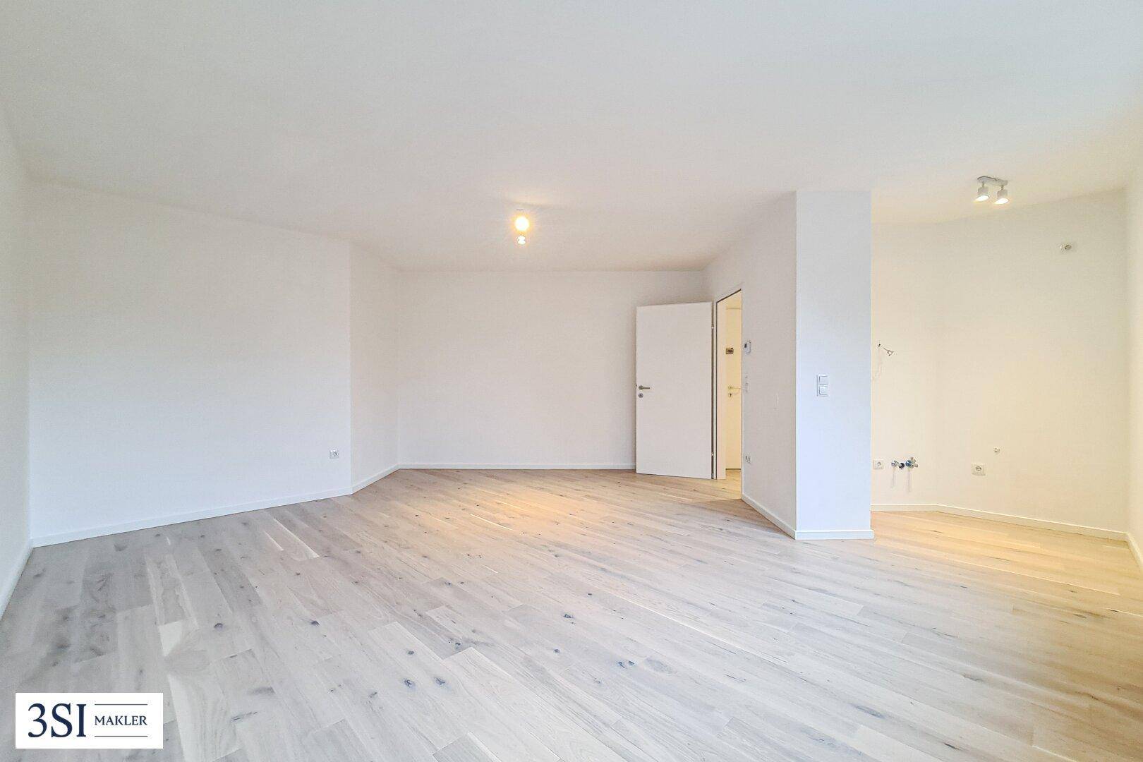 Geräumiges, helles Zimmer mit hellem Holzboden und weiß gestrichenen Wänden.