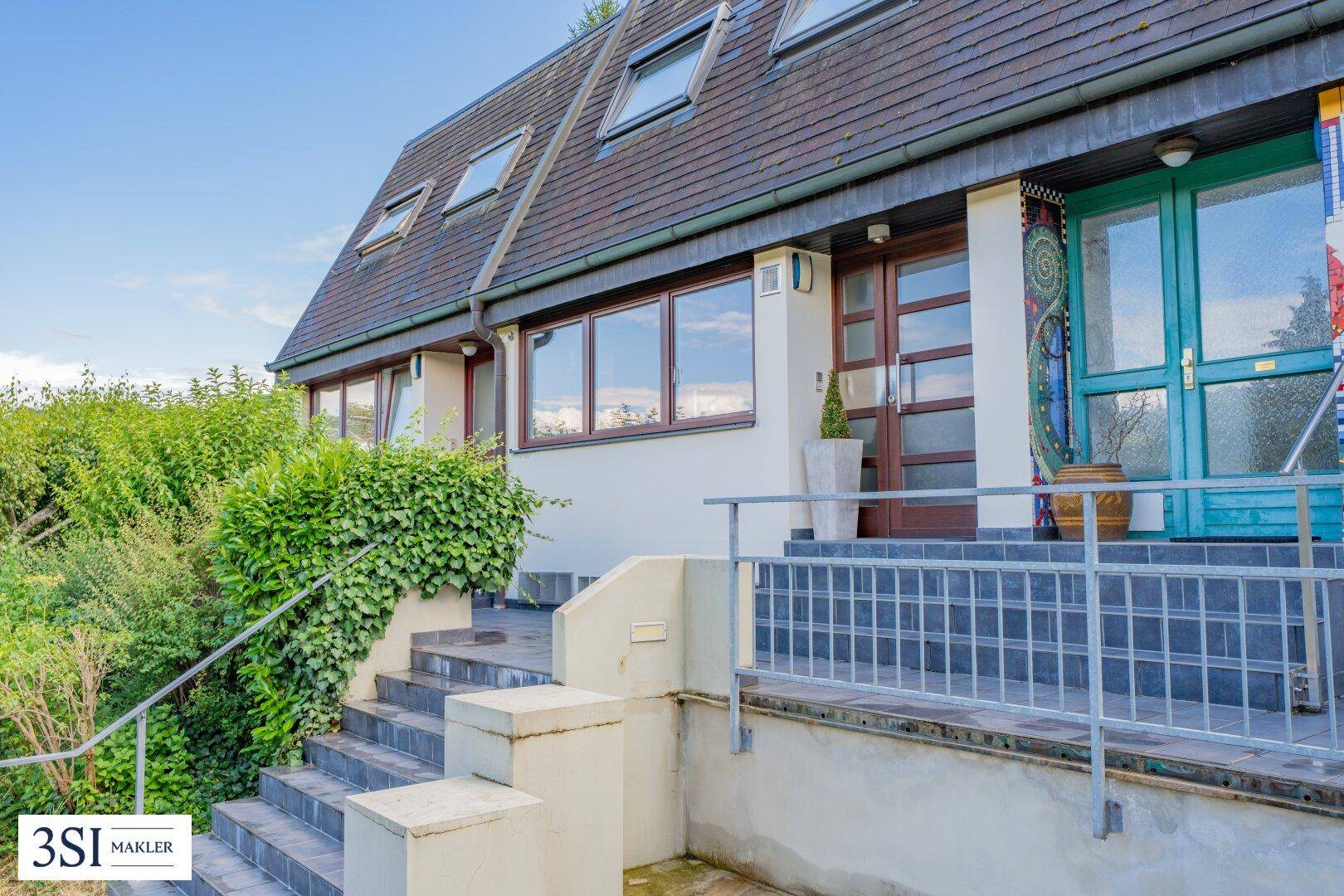 Eingangsbereich eines Hauses mit Treppe, Geländer und einer blauen Eingangstür.