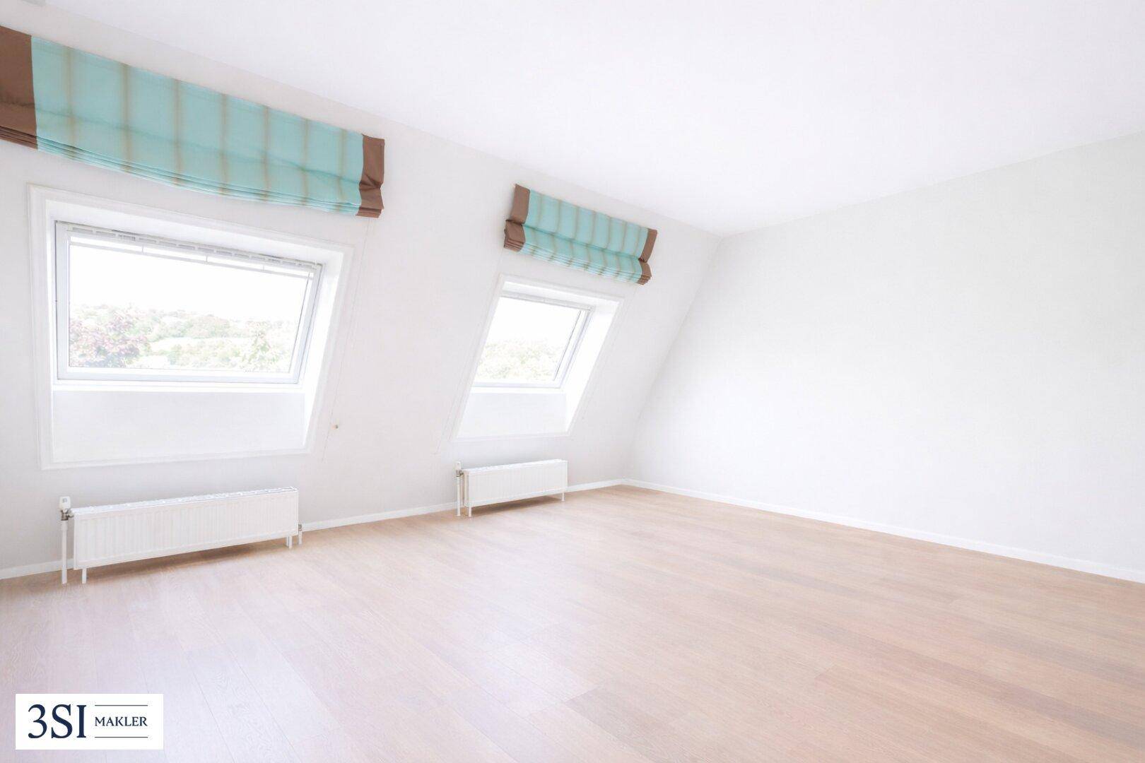 Helles Zimmer mit Dachschrägen und zwei Dachfenstern, ausgestattet mit Rollos.