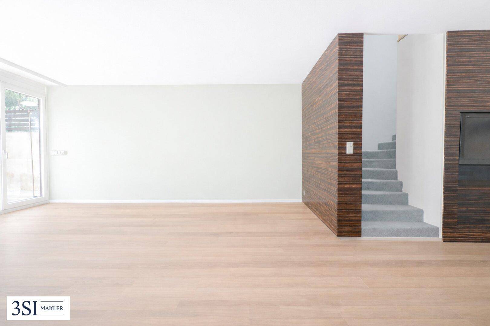 Geräumiger, heller Raum mit Holzvertäfelung und einer Treppe, die in eine obere Etage führt.