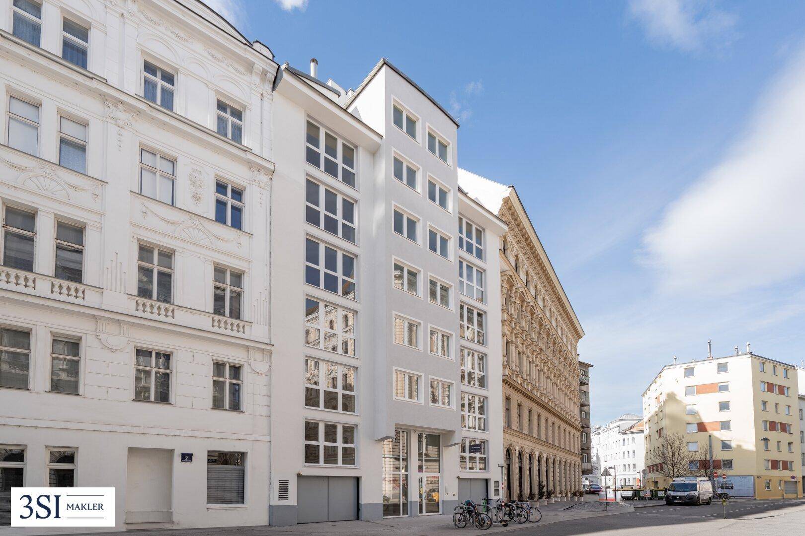 Moderne Wohngebäude mit vielen Fenstern in einer städtischen Umgebung.