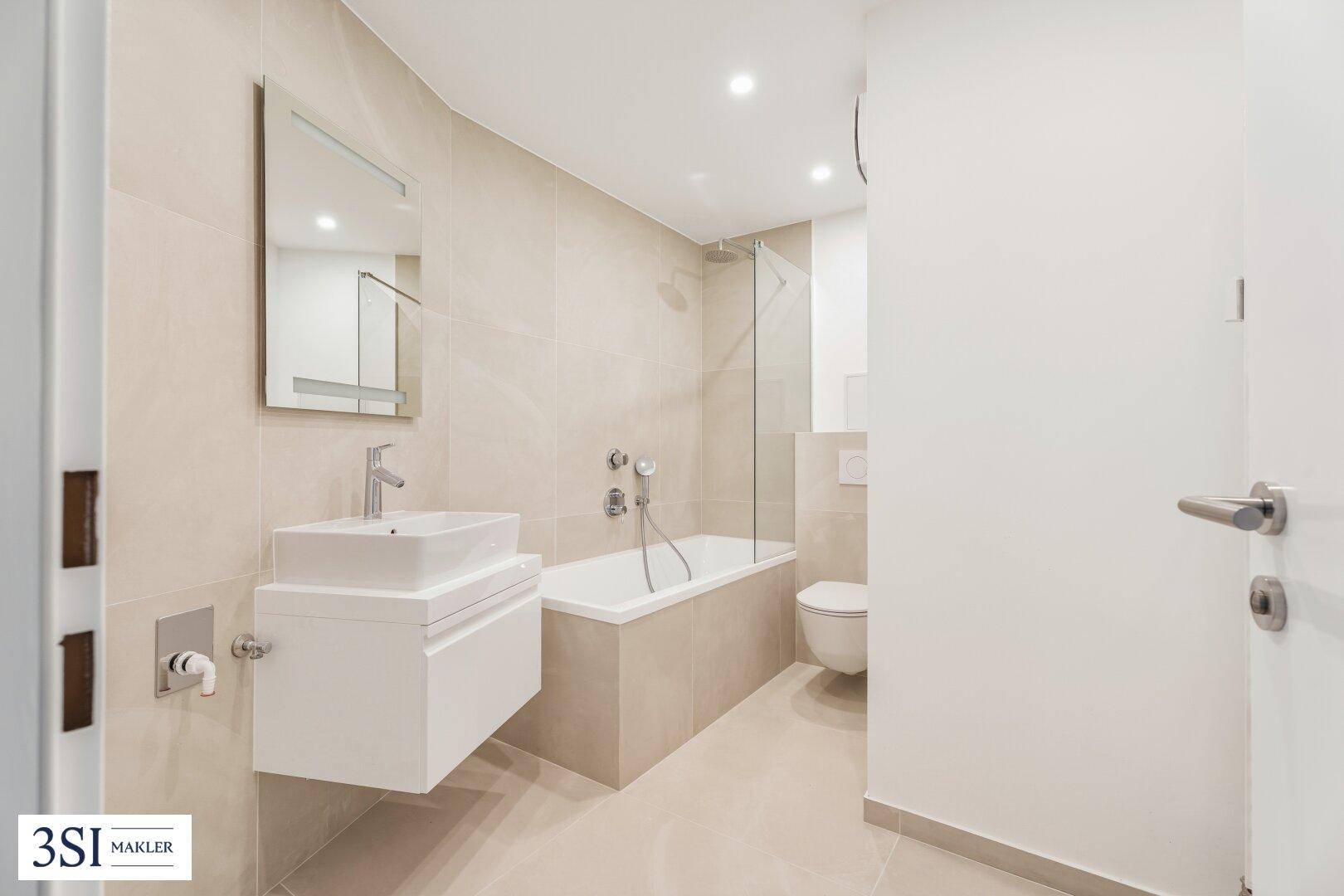 Modernes Badezimmer mit Badewanne, Dusche und hellem Fliesenboden.