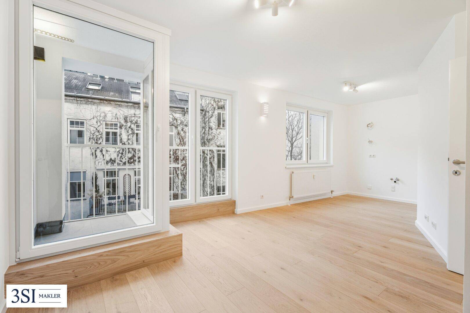 Heller Wohnraum mit Parkettboden und offenem Zugang zu einem französischen Balkon.